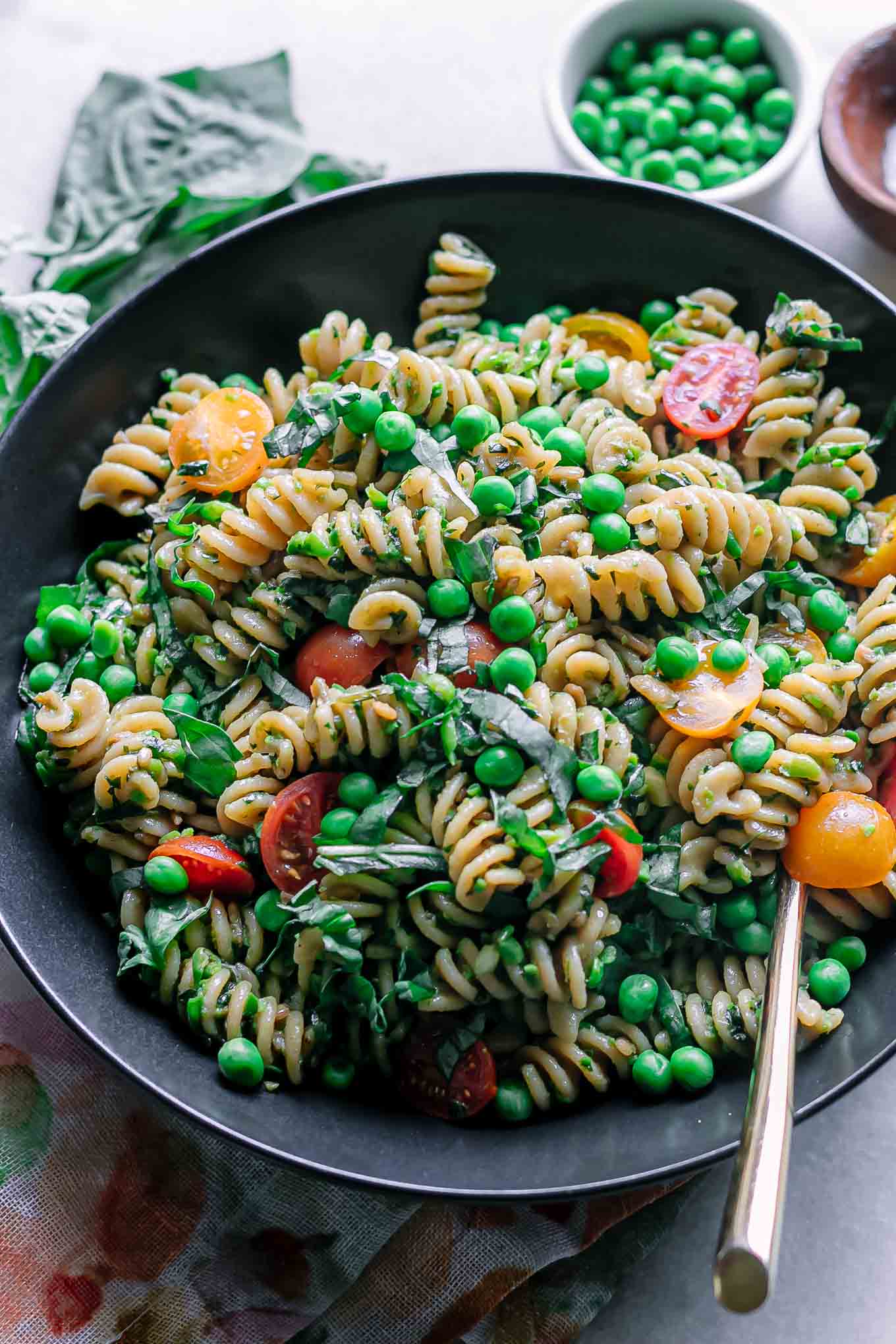 a bowl of pea pesto pasta on a table with a gold fork