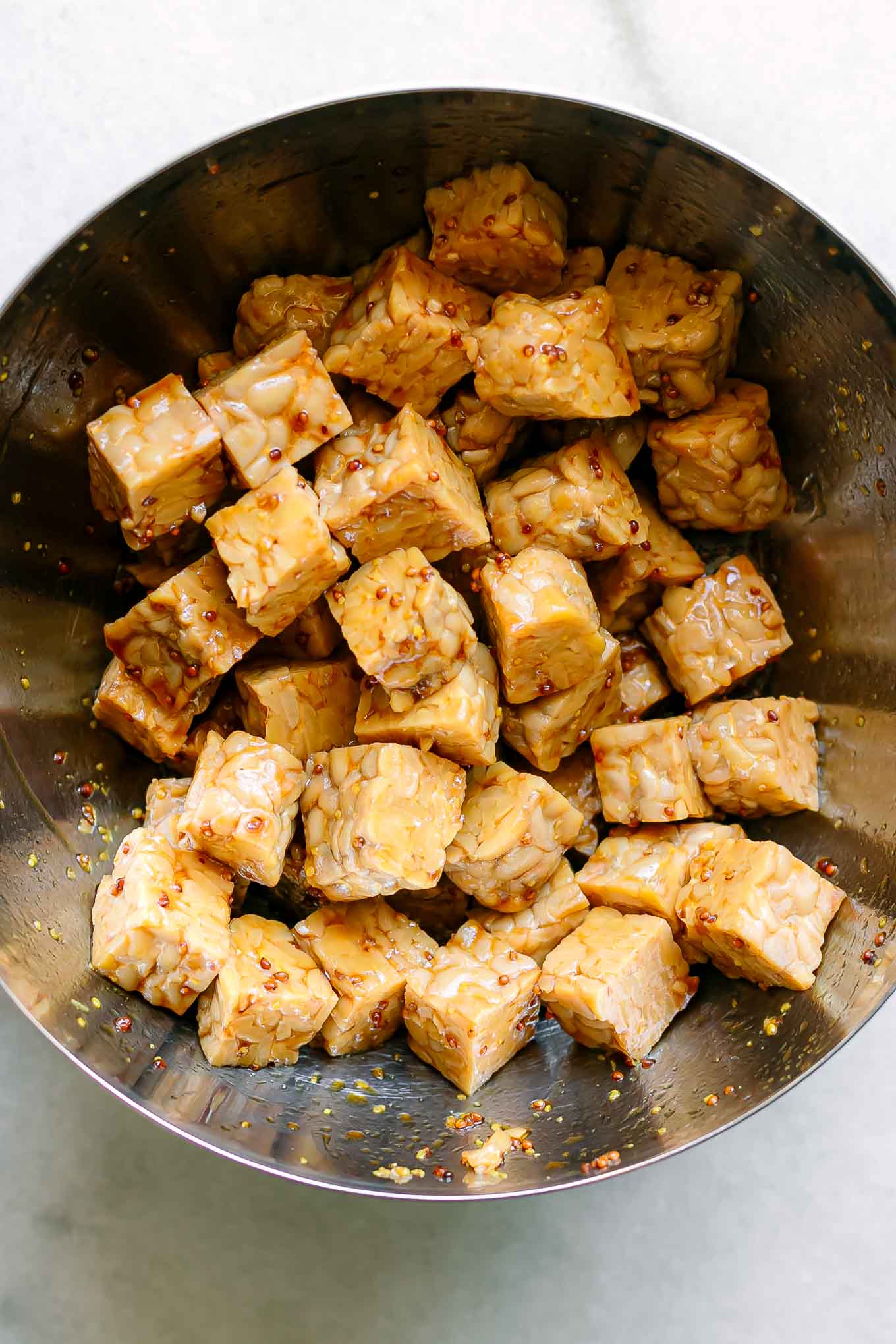 a bowl of tempeh marinating in sauce on a white table