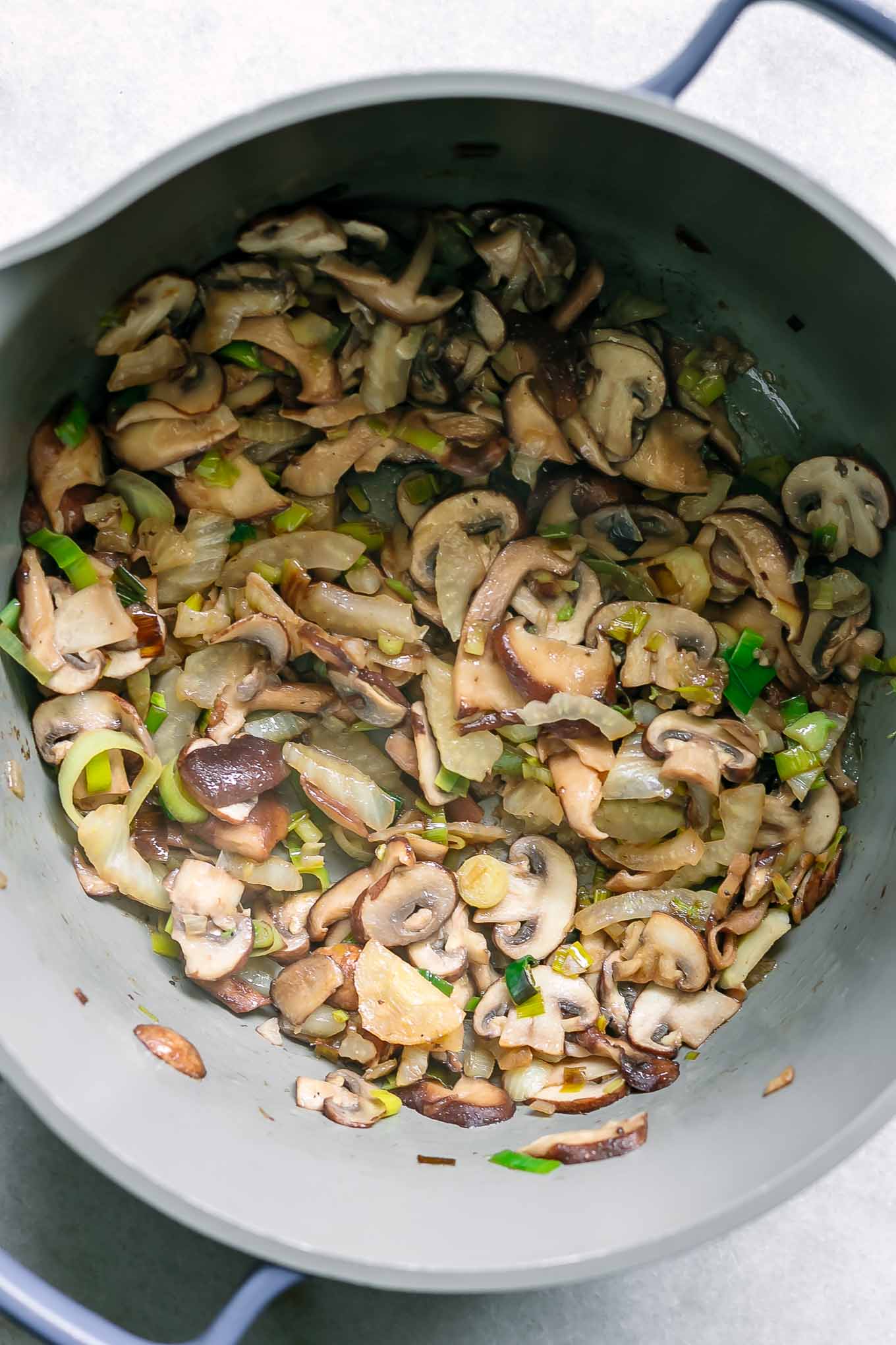 a large pot with cooked mushrooms, fennel, leeks, and garlic