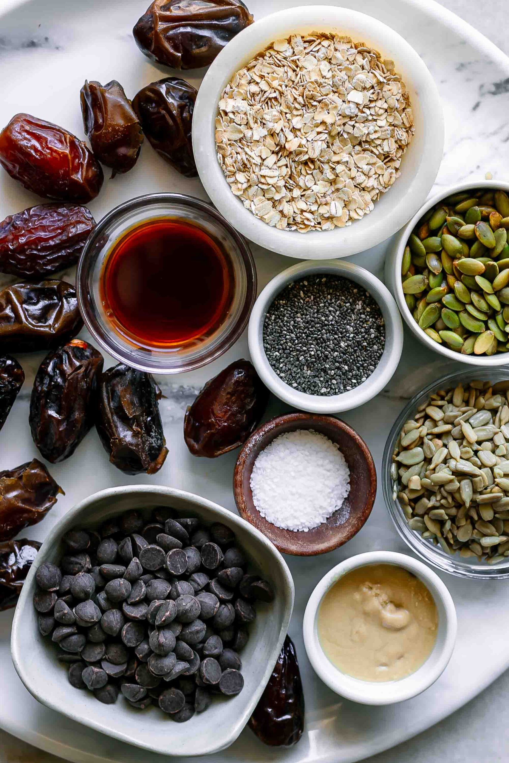 bowls of tahini, dates, pumpkin seeds, sunflower seeds, chia seeds, vegan chocolate chips, dates for snack balls