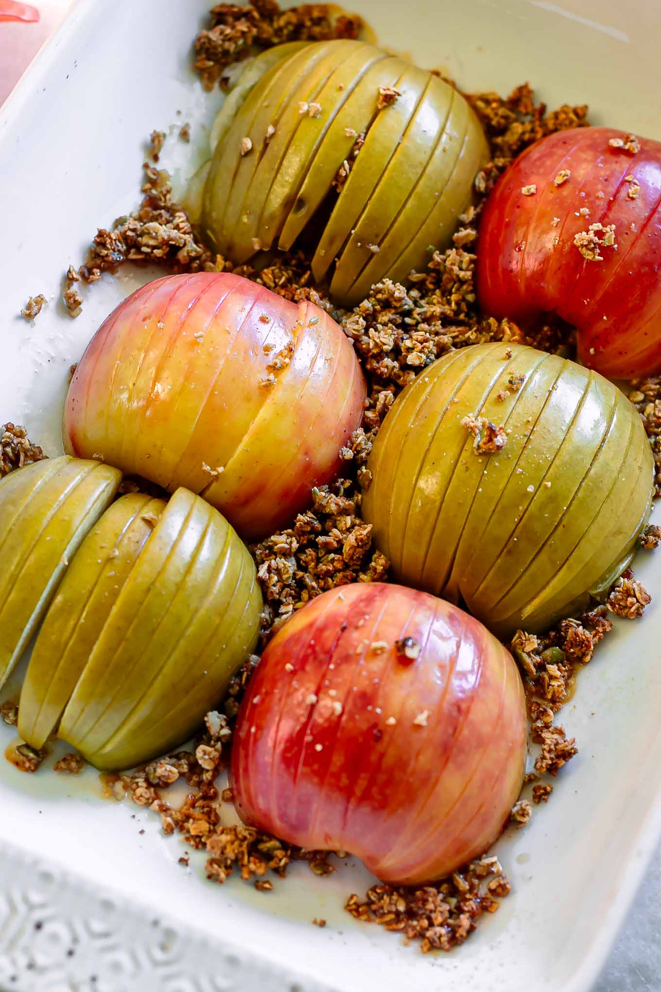 cut baked apples with granola in a white baking dish