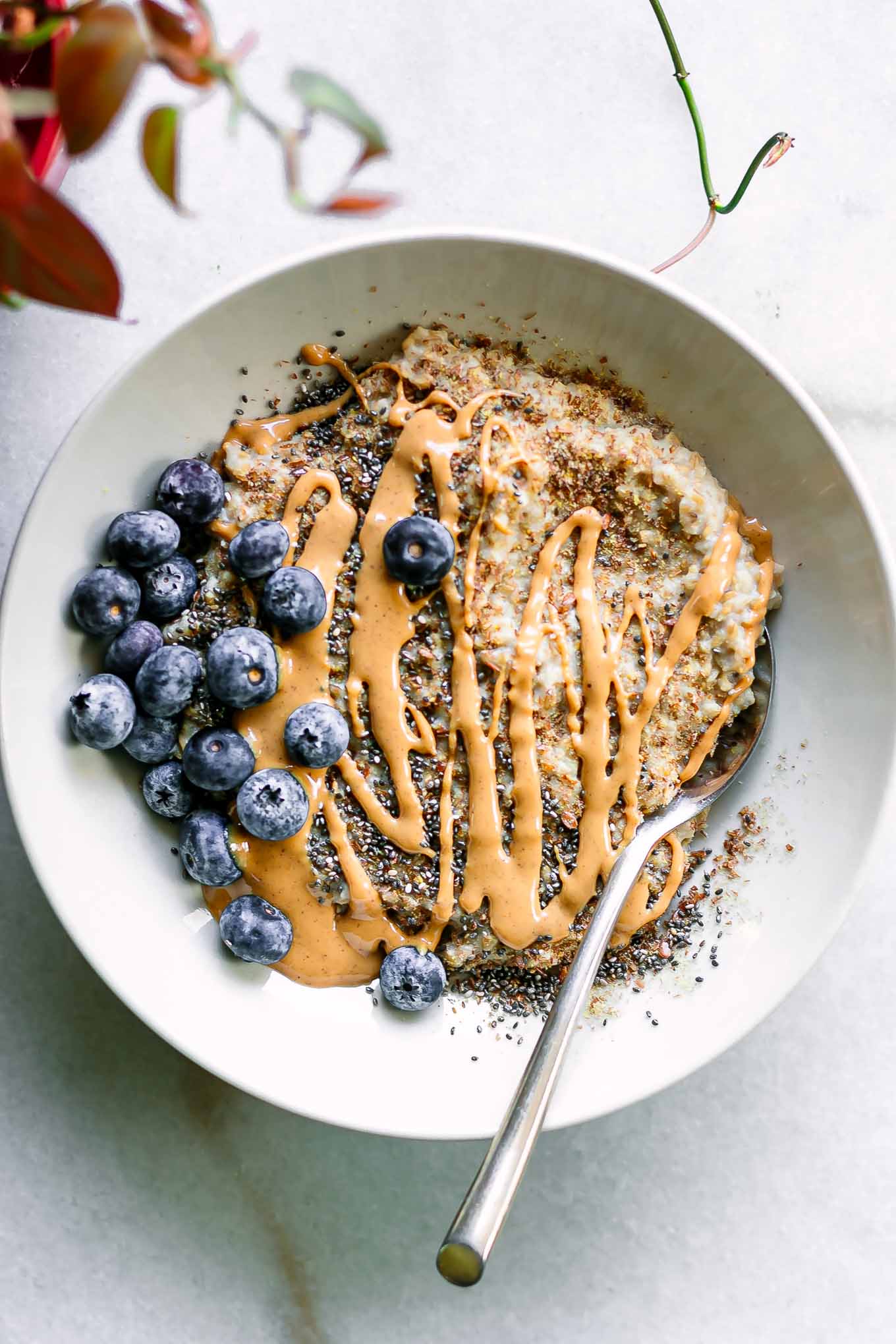 a bowl of steel cut oats with blueberries and peanut butter drizzle